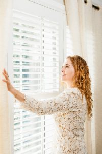 woman next to window blinds