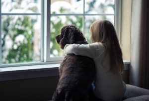 child with dog looking out window