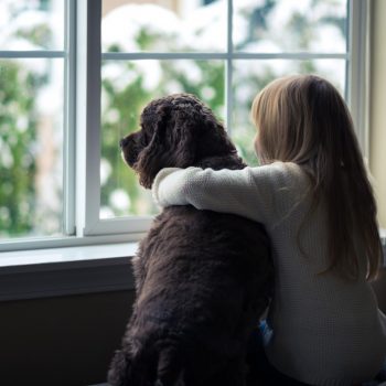 child with dog looking out window